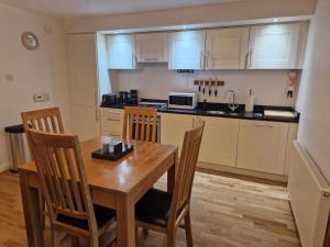 a kitchen with a wooden table and chairs and a counter at Glen Mor Apartment with pool on site in Fort Augustus