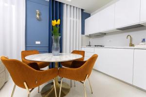 eine Küche mit einem Tisch mit Stühlen und einer Vase mit gelben Blumen in der Unterkunft Luxury apartment-Corso Malta by Alux38 in Neapel