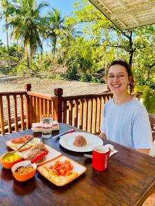 Una mujer sentada en una mesa con comida. en Berg House Unawatuna, en Galle
