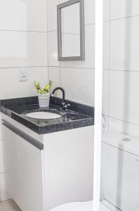 a white bathroom with a sink and a mirror at Callista Residence Flat in Porto De Galinhas