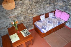 a small bedroom with a bed and a table at Casal São João Cottages in Fajã da Ovelha