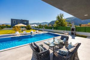 a swimming pool with a table and chairs next to a house at Villa Grand Yasar 3 in Okçular