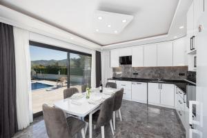 a kitchen with a table and chairs and a large window at Villa Grand Yasar 3 in Okçular