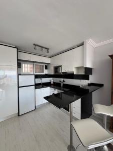 a kitchen with white cabinets and black counter tops at El Apartamento de Cristian 4 in Benidorm