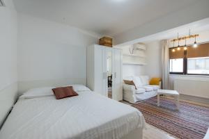 een witte slaapkamer met een bed en een stoel bij Concept Studio Haven 19 in Boekarest