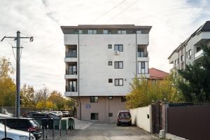 een hoog wit gebouw met auto's geparkeerd op een parkeerplaats bij Concept Studio Haven 19 in Boekarest