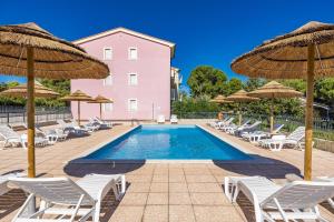 a swimming pool with chairs and umbrellas at Residence Kamenjak Runke in Premantura