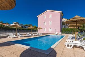 a swimming pool with chairs and umbrellas at Residence Kamenjak Runke in Premantura