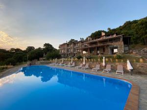 a swimming pool with chairs and a hotel in the background at Dohos Hotel in Karítsa