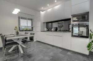 a kitchen with white cabinets and a table with chairs at Austriacka Apartamenty 4 in Koszalin +6 photos