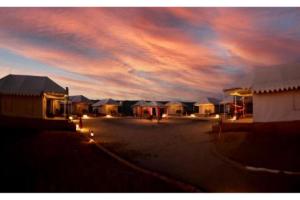 a group of huts with a cloudy sky at night at The Ker desert camp in Jaisalmer