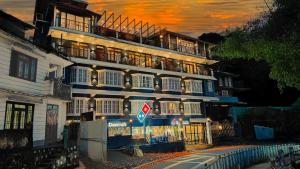 噶伦堡Mount Polaris Suites & Spa的一座高大的白色建筑,背面有日落