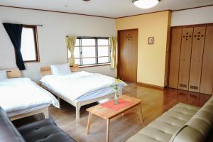 a room with two beds and a couch and a table at Oyado HALUBALL in Takayama