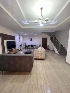 a large living room with a couch and a television at Bustal Homes-home away 4RM home in Abuja