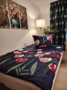 a bed with a blue comforter with pink flowers at Rhein Ferienwohnung 3-Zimmer Garten Free Parking Netflix Premium Disney Premium in Koblenz