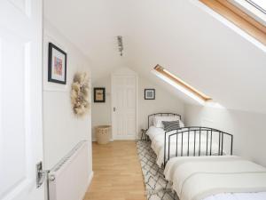 Dos camas en una habitación con paredes blancas. en The Palms, en Pwllheli