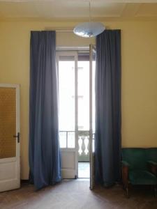 een kamer met een raam met blauwe gordijnen en een stoel bij Appartamento Teatro Duse in Bergamo