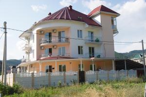 una gran casa amarilla con techo rojo en Edelveis Guest House, en Lazarevskoye