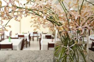 un vaso pieno di fiori rosa seduto su un tavolo di Hotel New Tokyo a Capitão Poço Altre 20 foto