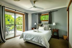 a bedroom with a white bed and a sliding glass door at Bella Vista Bellingen in Bellingen