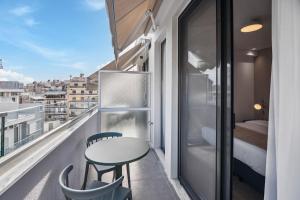 a balcony with a table and chairs and a bed at Limehome Piraeus Olive in Piraeus +42 photos