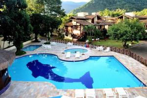 a large swimming pool with chairs and a resort at Condomínio Canto do Mar a 50 Metros Praia de Maresias in Maresias