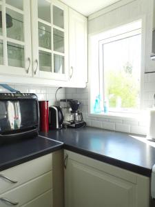 a kitchen with white cabinets and a black counter top at 1A, Stuga med 50m till strand in Byxelkrok
