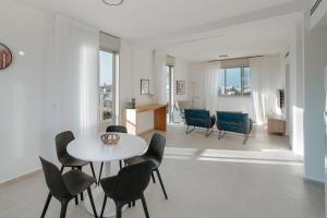 a white living room with a table and chairs at JL Gordon Residence - MAMAD in Tel Aviv