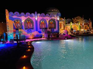 a building with a swimming pool at night at Kato Dool Wellness Resort in Aswan