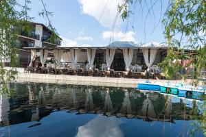 a hotel with tables and chairs next to a body of water at Complex Pescăresc Gura Repezii Borșa in Borşa +37 photos