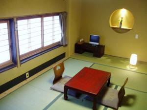 a room with a table and a chair and a television at Inn Kawashima in Kyoto