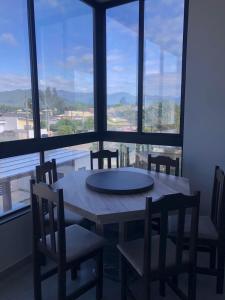 a table and chairs in a room with a large window at Residencial ISL - Praia da Pinheira SC in Palhoça
