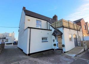 a white building with a window and a door at Harbour Heights by Coast & Country Stays in Seahouses