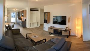 a living room with a couch and a tv at Haus Albatros EG - Exklusive Fewo für 4 Personen in Dangast