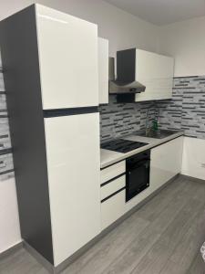 a kitchen with white cabinets and a black and white refrigerator at Appartamento Tortona in Tortona