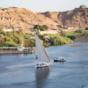 un barco con una vela en un río en ACHERTOD Nubian House, en Naj‘ al Maḩaţţah