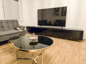 a living room with a tv and a glass coffee table at Apartment mit Aussicht über Osterode in Osterode