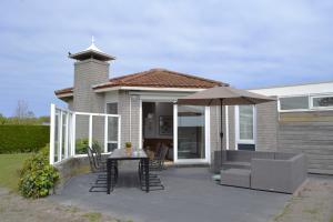 a patio with an umbrella and a table and chairs at Golfvilla 38 in Hollum