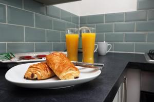 a plate with two croissants and two glasses of orange juice at Escape to Comfort 3BR in Avonmouth +49 photos