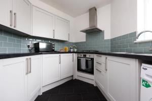 a kitchen with white cabinets and a black floor at Escape to Comfort 3BR in Avonmouth