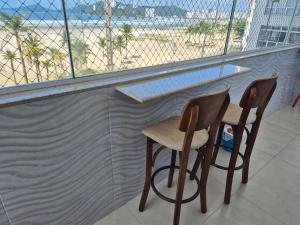 two chairs at a bar with a view of the beach at Verdadeiro pé na areia TOP in Santos