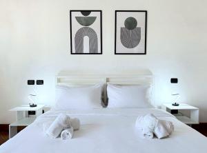 a bedroom with a white bed with three pictures on the wall at Horizon View Apartment - panoramic terrace in Fiumicino Airport