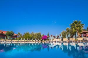 a large swimming pool with chairs and palm trees at Sundia By Liberty Suncity in Oludeniz
