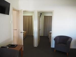 a hotel room with a chair and a bedroom at Pittsworth Motor Inn in Pittsworth