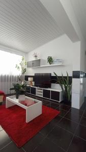 a living room with a tv and a red rug at Kanela Guest House in Machico