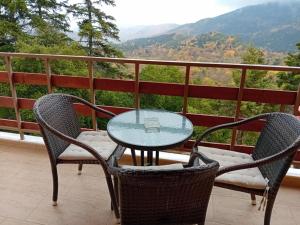 a glass table and chairs on a balcony with a view at Το Πανδοχείο Της Παυλιανης in Pavliani