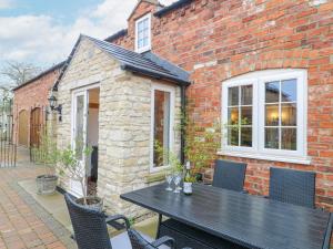 a brick house with a black table and chairs at Church Barn in Grantham