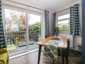 a dining room with a table and a balcony at Trearddur House Cottage in Holyhead