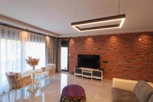a living room with a brick wall and a television at Adrasan Villa Adrasya in Olympos
