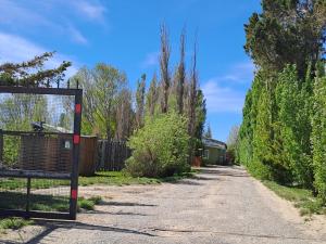 Un camino de tierra con una valla y árboles. en La Finca 1, en Río Gallegos